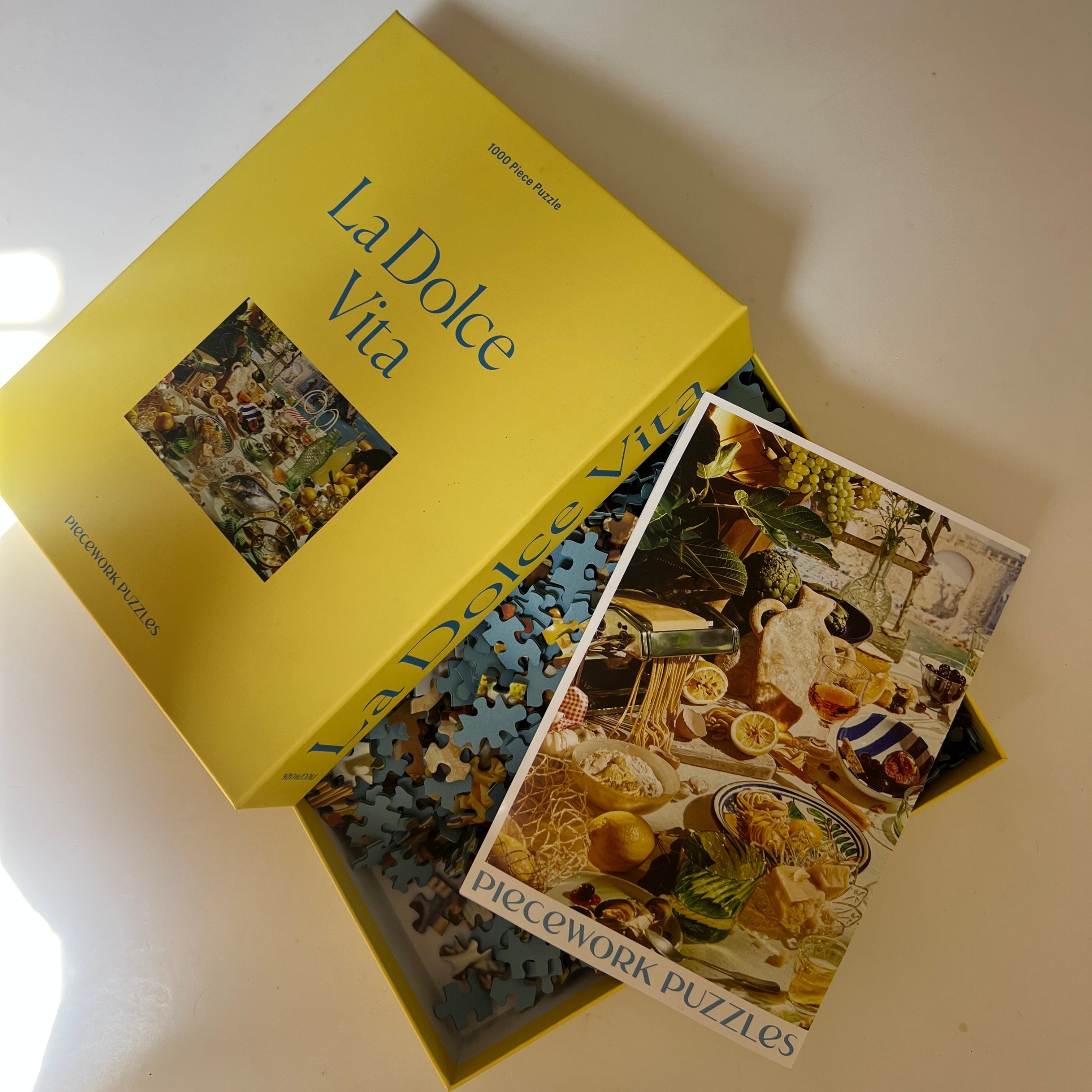Open box of 'La Dolce Vita' puzzle with a piece on top